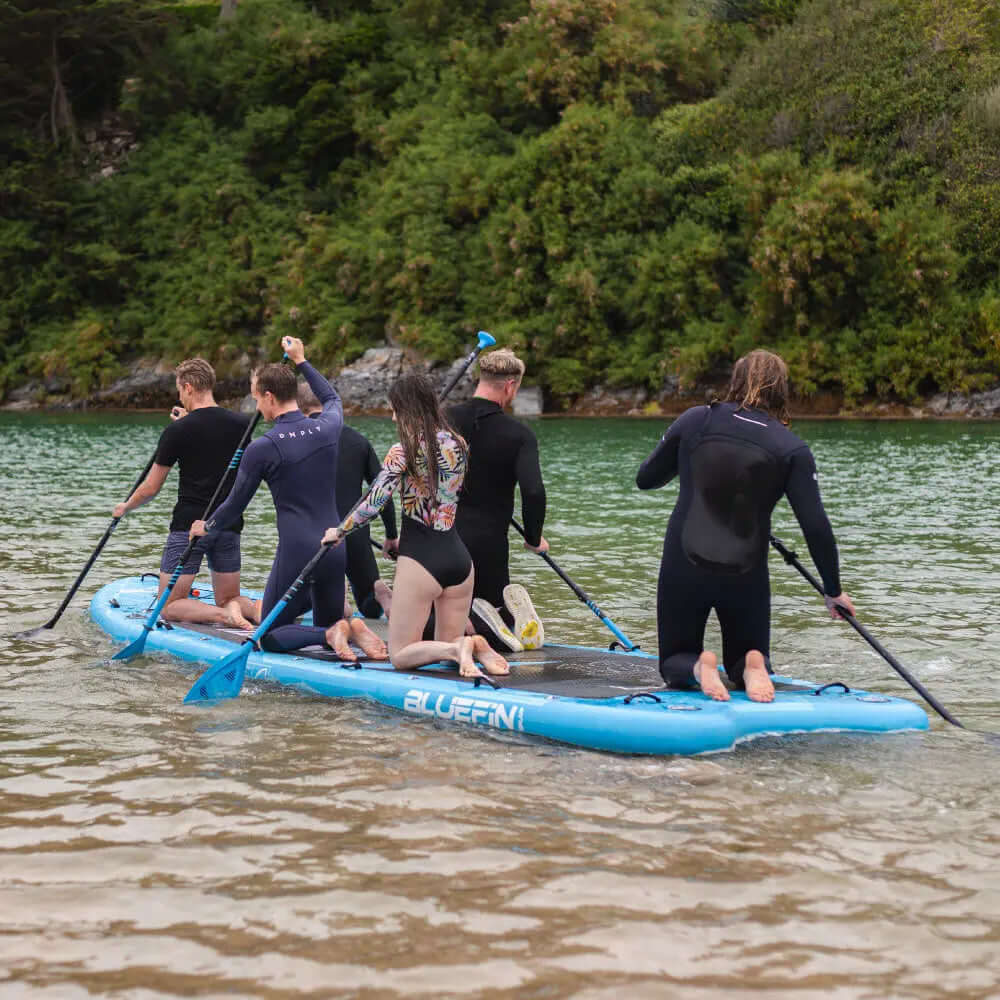 Zes personen peddelen samen op de blauwe Mammoth SUP